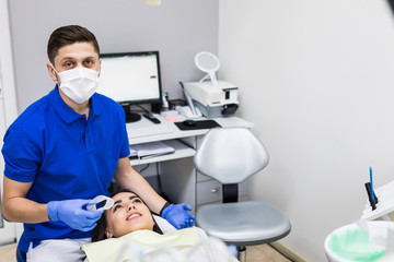 Portrait of man dentist and female patient wear kapa to make teeth whitening in clinic. Teeth whitening procedure