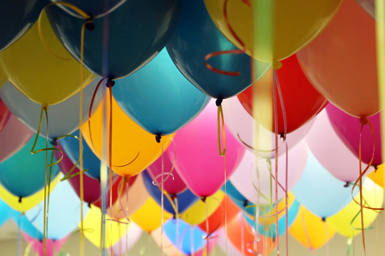 Helium balloons with ribbons in the office. Colorful festive background for birthday celebration, corporate party