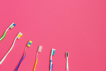 Set of different toothbrushes on pink background.
