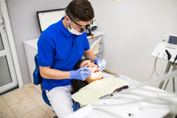 Close-up of girl with open mouth during oral check up of teeth at the dentist.