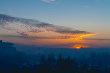 Obraz premium Cityscape with wonderful varicolored vivid dawn. Amazing peaceful cloudy sky above silhouettes of city buildings. Atmospheric background of orange sunrise. Sunset landscape. Copy space.
