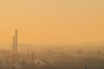 Smog among silhouettes of buildings on sunrise. Smokestack in dawn sky. Environmental pollution on...