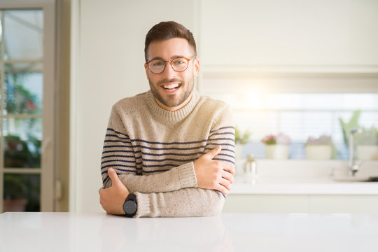 Young handsome man wearing glasses at home happy face smiling with crossed arms looking at the camera. Positive person.