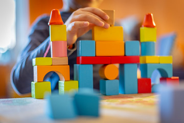 a child plays with colored wooden blocks at home.kid plays and builds buildings and towers with wooden colored blocks.