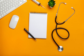Top view of a doctor's table with notepad and pen stethoscope, keyboard, prescription and pills, a...