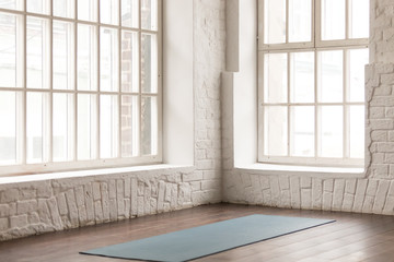 Fototapeta na wymiar Yoga mat on wooden floor in empty room in yoga studio