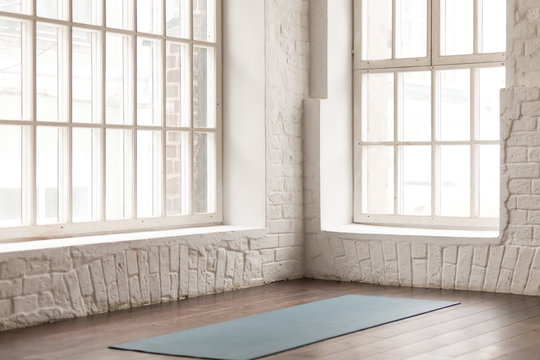 Yoga mat on wooden floor in empty room in yoga studio