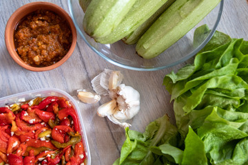 Homemade pickled paprika with garlic, zucchini, lettuce, garlic cloves and sauce on wooden table
