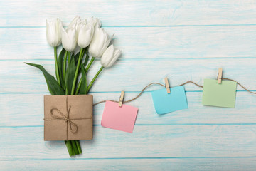 A bouquet of white tulips and envelope with a color stickers with clothespins on a rope and blue wooden boards