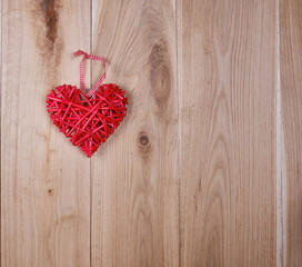 wooden background of oak boards and a red wicker heart