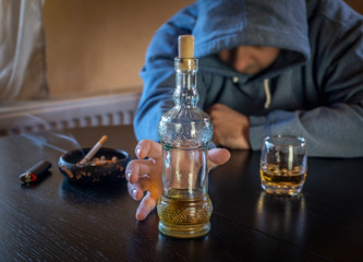 An alcohol addict provides a hand to the bottle