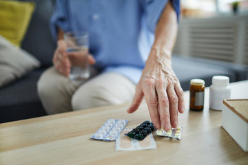 Close up of unrecognizable senior woman taking pills and medication off table at home, copy space - obrazy, fototapety, plakaty