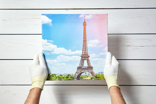 Photography printed on canvas with gallery wrap method of canvas stretching in male hands. Image of Eiffel Tower (Paris, France)