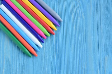 Fototapeta premium Bright colorful pens with selective focus on blue textured background. Back to school flat lay. Beautiful rainbow pens on blue wooden backdrop. Multicolored education tools for drawing 