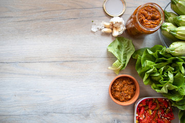 Homemade pickled paprika with garlic, zucchini, lettuce, garlic cloves and sauce on wooden table, with copy space