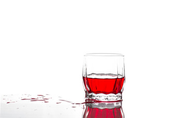 Splash of red juice, wine in a glass ribbed whiskey glass on a white background