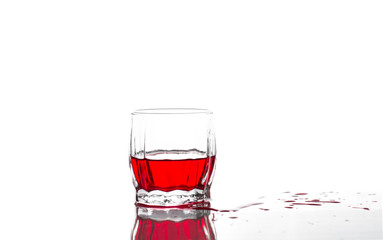 Splash of red juice, wine in a glass ribbed whiskey glass on a white background