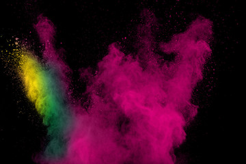 Color powder explosion cloud on black background. Freeze motion of color dust  particles splashing.