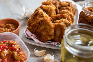 Breaded soya chunks, homemade pickled paprika with garlic, pickled cucumber, garlic cloves and sauce on wooden table