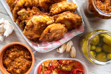 Breaded soya chunks, homemade pickled paprika with garlic, pickled cucumber, garlic cloves and sauce on wooden table