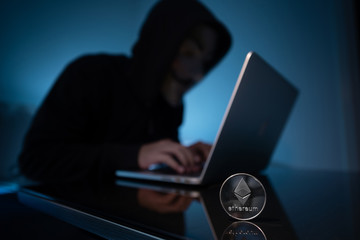 Hacker try to hack ethereum blockchain system with laptop in dark room