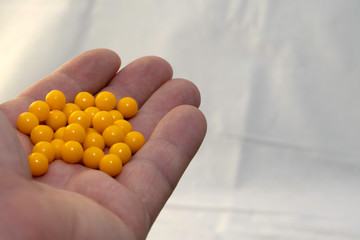 hand holding a handful of yellow pills