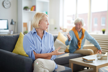 Fototapeta premium Portrait of modern senior couple fighting focus on yelling senior woman in foreground, copy space