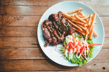 Black Pepper Pork Steak,salad mixed,French fries set on wood table background.