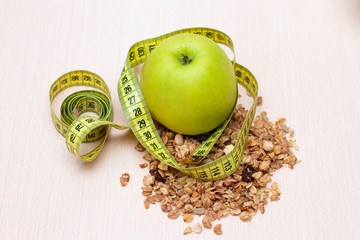 Apple, muesli and measuring tape on the table. Diet, proper nutrition