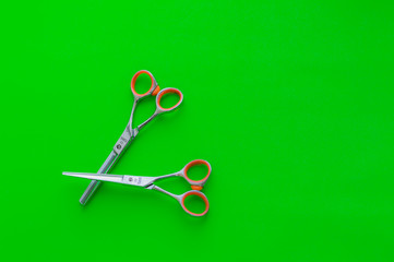 Barbershop. Tools stylist. Two metal scissors on a bright green background. Copy space.