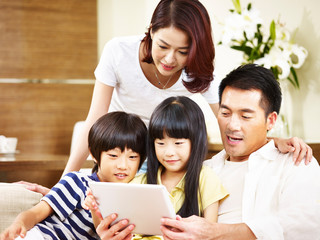 asian family with two children using digital tablet together