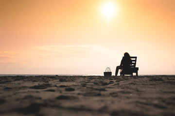 Fototapeta na wymiar Girl is sitting on the sun lounger on the beach at sunset. Summer concept.