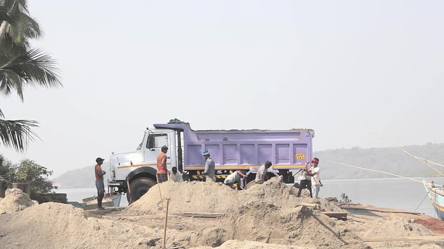 Querim, Goa/India - 10.01.2019: Indian workers load sand into a truck with shovels