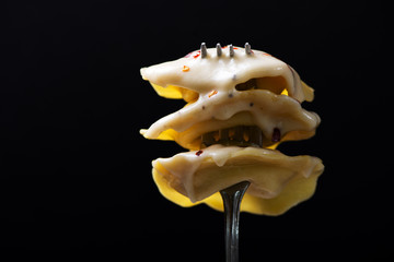 Naklejka premium Ravioli in Cheese Sauce Speared on Fork with Black Background