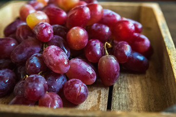 A large bunch of ripe grapes on a background of a dark textured wooden table. Grapes close up and copy space.
