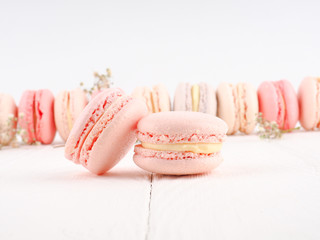 Colorful French or Italian macarons stack on white wood table with copy space for background. Dessert for served with afternoon tea or coffee break.