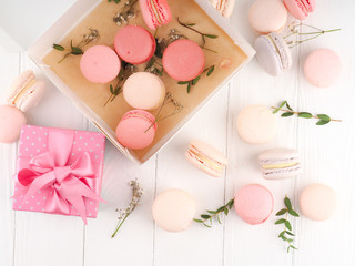 Colorful French or Italian macarons stack on white wood table with copy space for background. Dessert for served with afternoon tea or coffee break.
