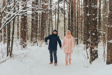 Fototapeta na wymiar A loving couple walks in the woods. Family walk in the winter forest