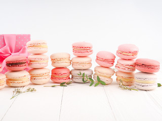 Colorful French or Italian macarons stack on white wood table with copy space for background. Dessert for served with afternoon tea or coffee break.