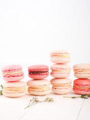 Fototapeta na wymiar Colorful French or Italian macarons stack on white wood table with copy space for background. Dessert for served with afternoon tea or coffee break.