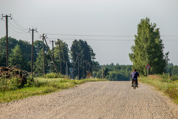 Obraz premium Landscape with rural road and man on moped..