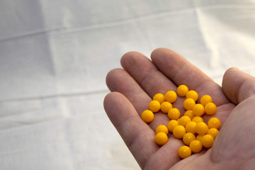 hand holding a handful of yellow pills