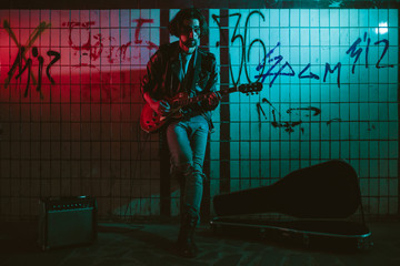 A street musician playing on guitar in the underpass. Vagrant lifestyle. Playing in the underpass...
