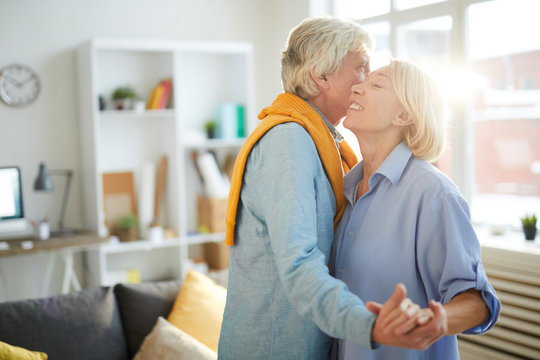 Waist up portrait of happy senior couple dancing at home in sunlight, copy space