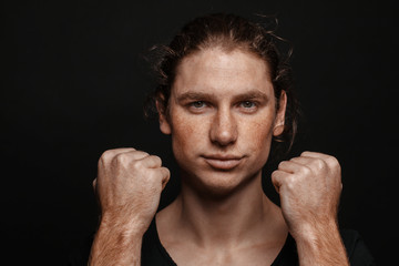 Portrait of a handsome long-haired man with drawn hair and freckles wearing a black T-shirt