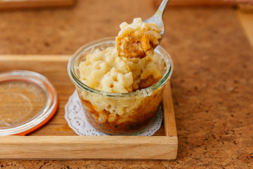 Female hand is scooping Macaroni Cheese Baked with meat sauce in glass bowl.