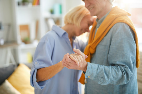 Side view portrait of happy senior couple dancing at home lit by sunlight, copy space