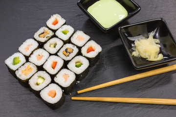 variations of maki sushi rolls with ginger and wasabi dip