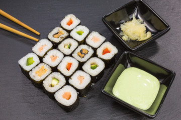 variations of maki sushi rolls with ginger and wasabi dip