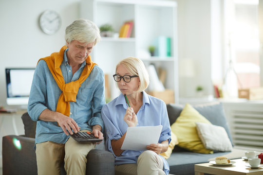 Portrait of contemporary mature couple calculating finances at home, copy space